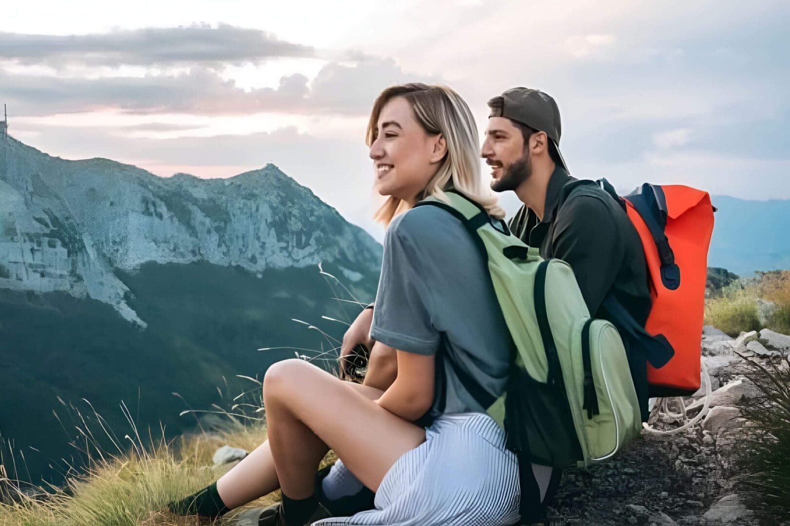 Two hikers enjoying a mountain view at sunset.