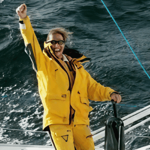 Person in a yellow rain jacket enjoying a boat ride on choppy waters.